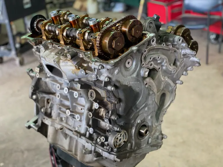 Engine long block on a stand in The Motorpool shop with the timing gears and camshafts exposed